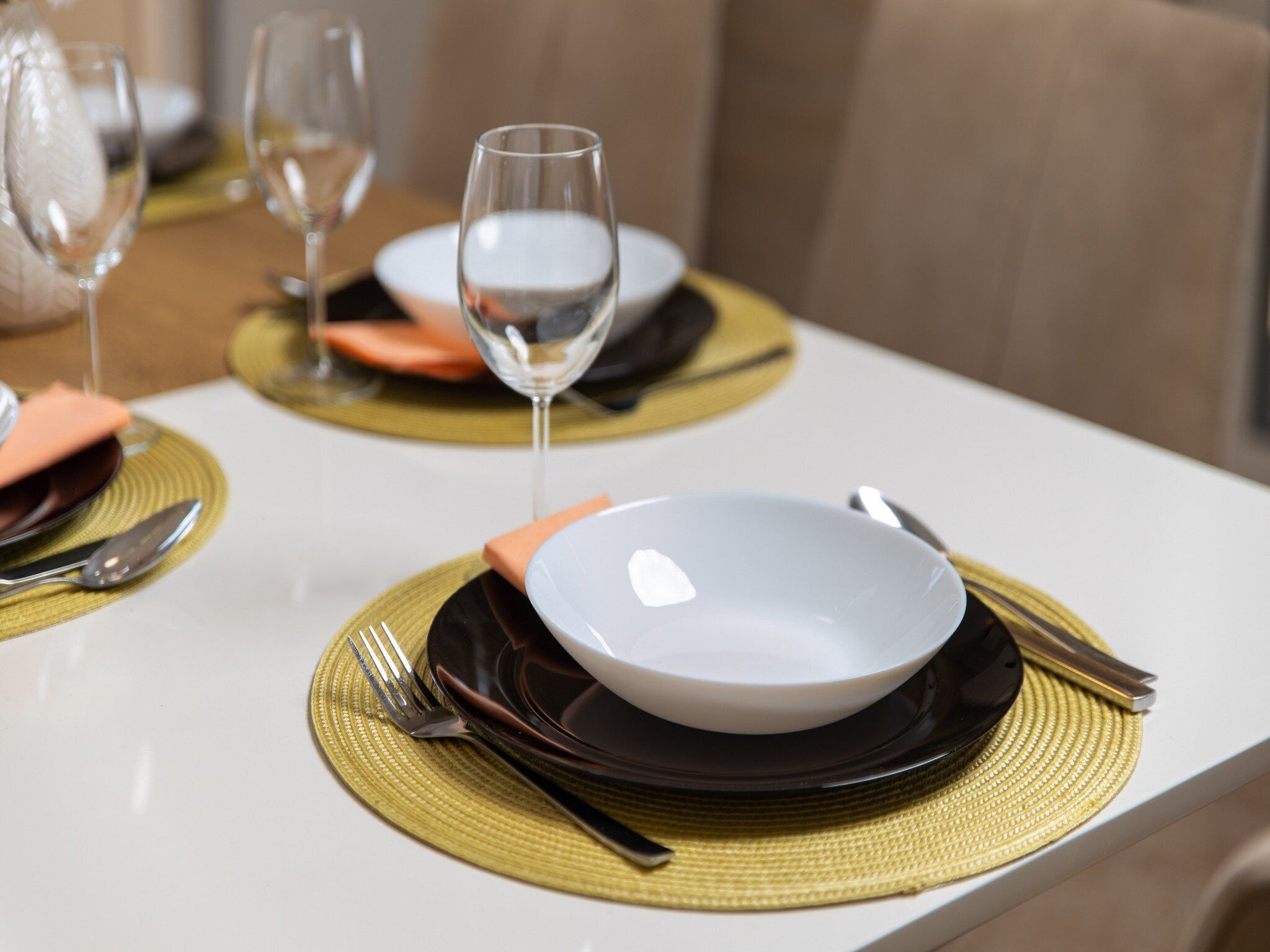A dining table set with plates, cutlery, and a glass of water.