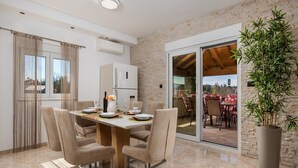 A dining area with a marble floor, beige chairs, a wooden table, and a potted plant. - Villa Lemily (Matulji)