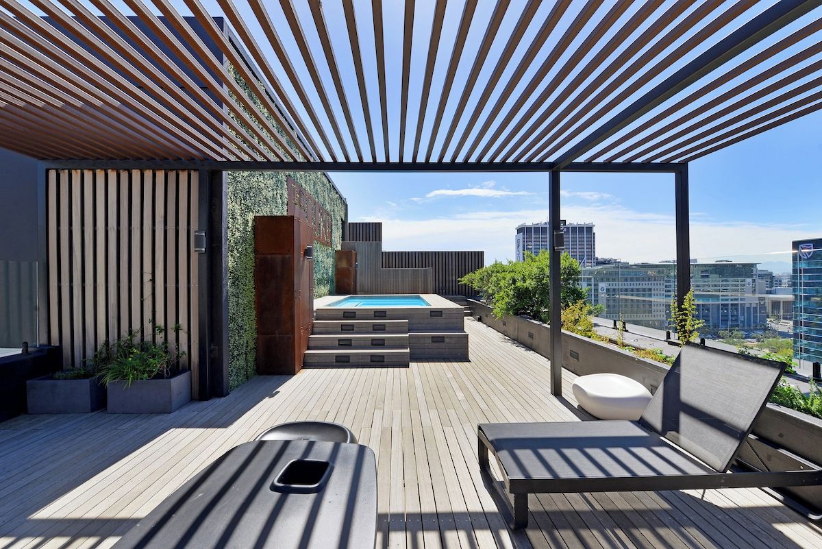 A rooftop terrace with a pool, seating, and a view of the city.