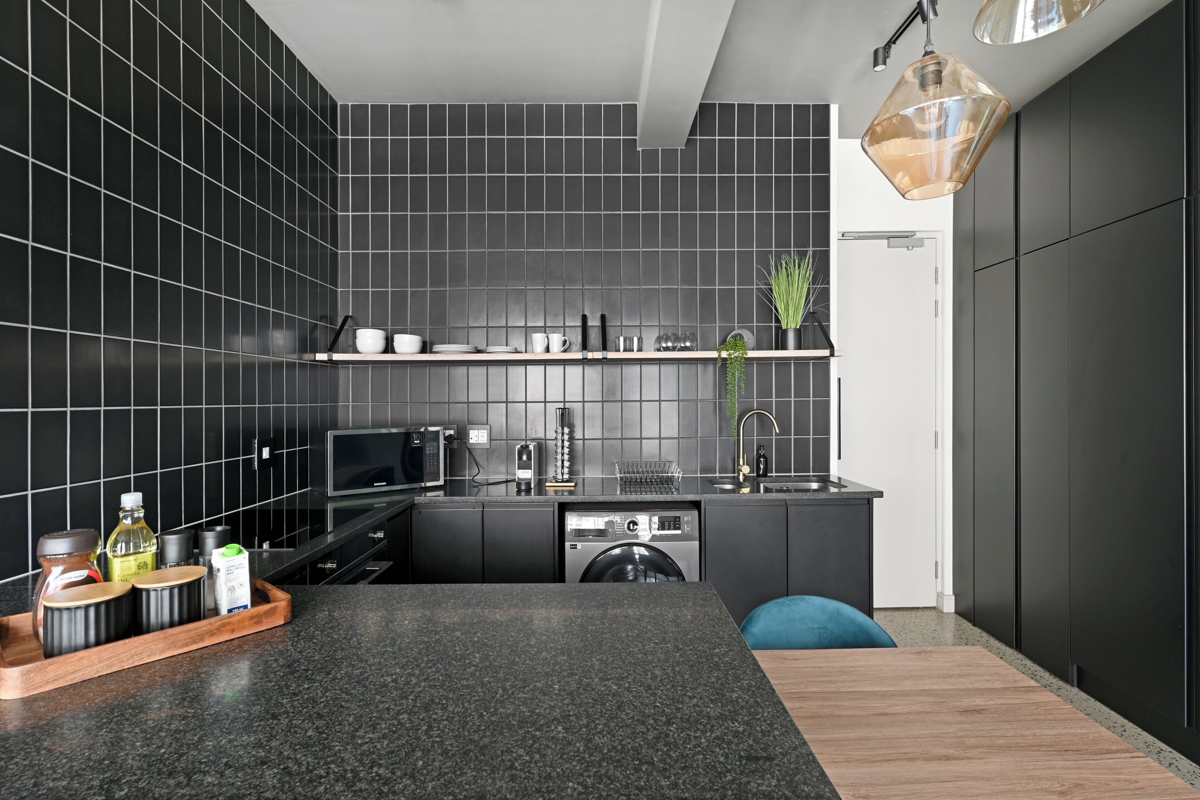 A modern kitchen with dark tiles, a wooden countertop, and a built-in dishwasher.