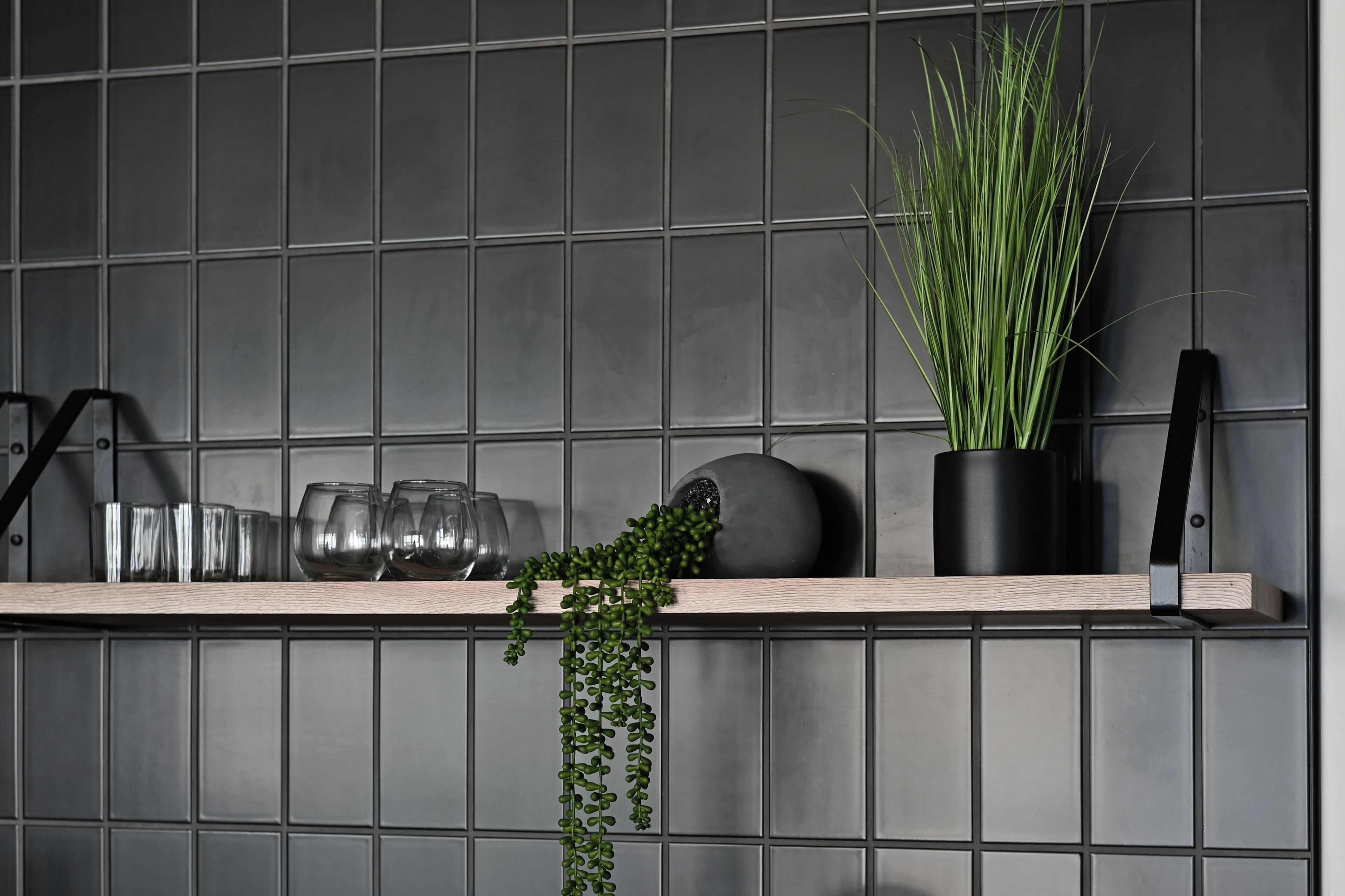 Una encimera de cocina con una planta en maceta, un cuchillo y varios vasos.