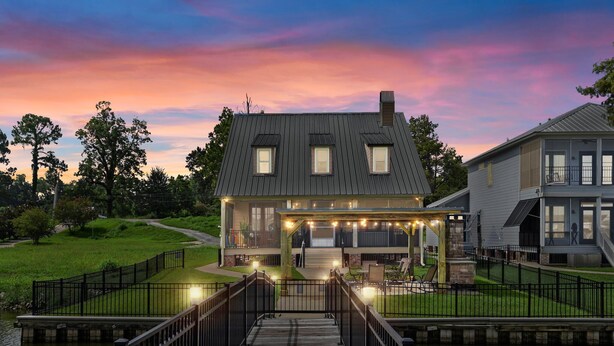A house with a covered porch, a wooden deck, and a pond. - False River Waterfront - Pets - Fire Pit - Porch (Ventress)
