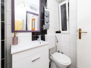 Ein modernes Badezimmer mit einem weißen Waschtisch, einem Spiegel, einer Toilette und einer Duschkabine.