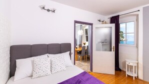 Un dormitorio con una cama, un edredón morado y vistas al mar a través de una ventana.