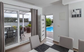 A modern living room with a glass door leading to a balcony with outdoor furniture and a pool. - Apartment Villa Andelka (Split)