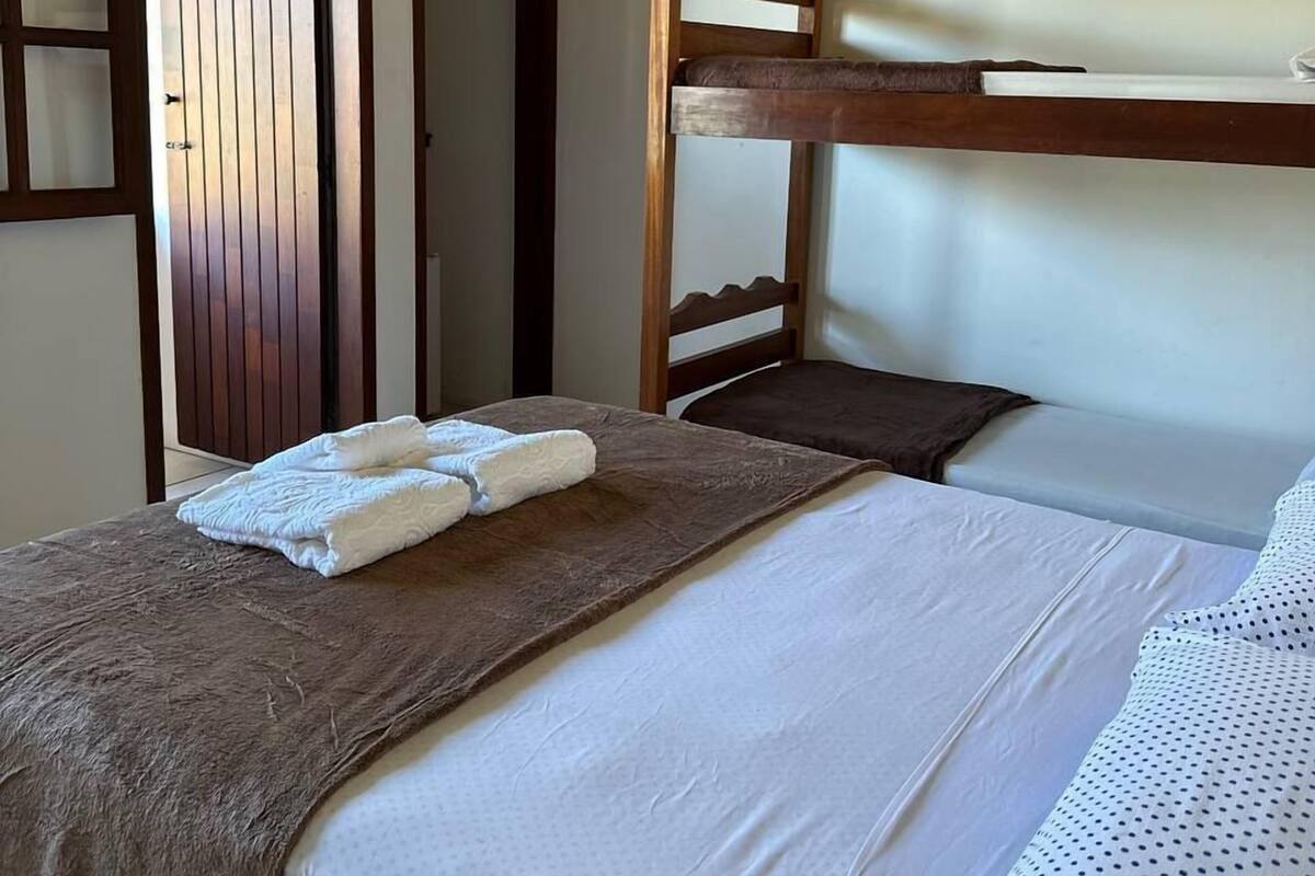 Une chambre avec un lit superposé, une porte en bois et un téléviseur fixé au mur.