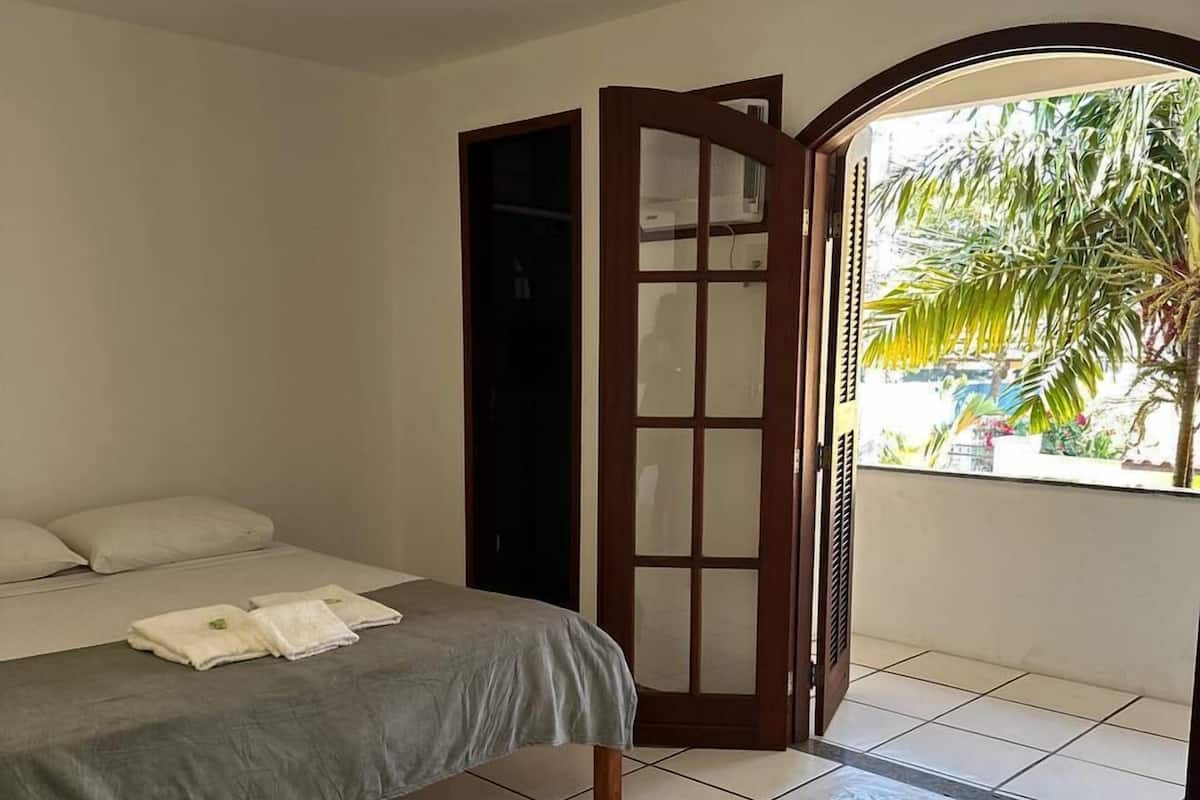 Une chambre avec un lit, une armoire et une vue sur des palmiers.