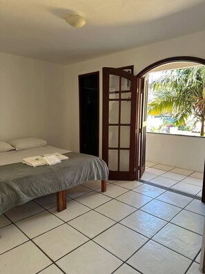 Een kamer met een bed, een kledingkast en uitzicht op palmbomen.