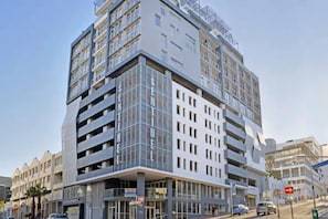 Un hôtel à plusieurs étages au design moderne, doté d’une entrée imposante et de nombreux balcons.