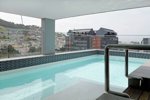 Une piscine sur le toit offrant une vue sur le paysage urbain, avec ses bâtiments et ses collines.