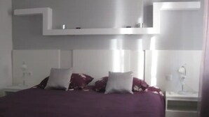 Ein modernes Schlafzimmer mit einem großen Bett, einem weißen Kopfende und Nachttischen mit Lampen.