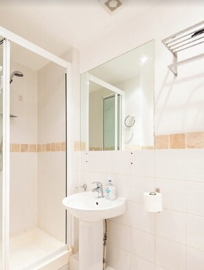 A bathroom with a sink, mirror, and shower. - Flat in Kensington  (London)