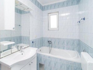 A bathroom with a bathtub, a sink, and a mirror. - Apartment Stipic Omis (Omis)