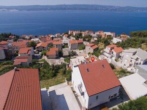 A coastal village with red-roofed houses, a clear view of the sea, and a red location marker. - Apartment Stipic Omis (Omis)