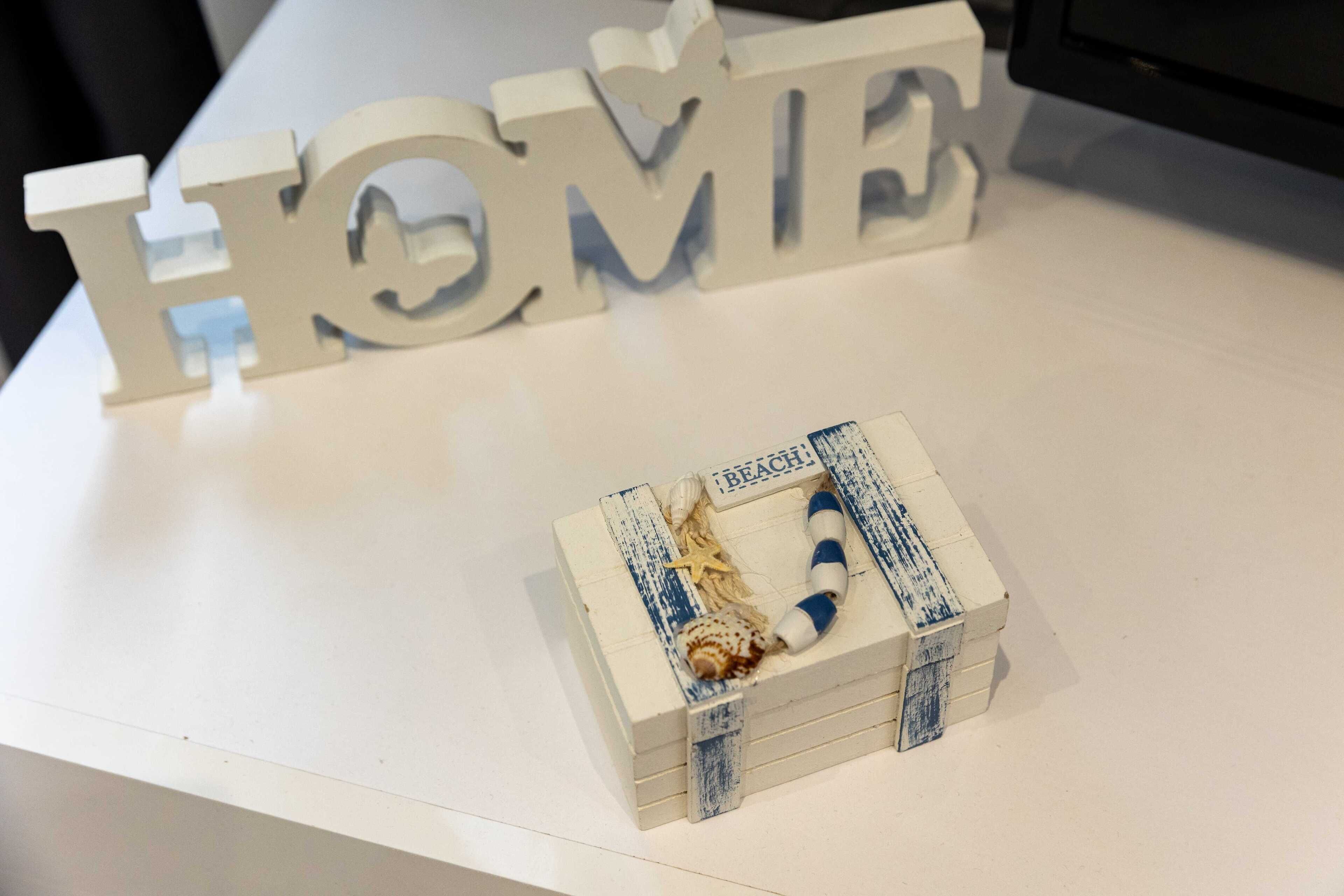 A white table with a decorative box labeled "BEACH" containing a starfish and a seashell.