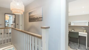 Un intérieur moderne avec un escalier, un tableau accroché au mur et un espace bureau.