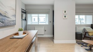 Un salon moderne avec une table basse en bois, une plante en pot et un grand tableau abstrait accroché au mur.