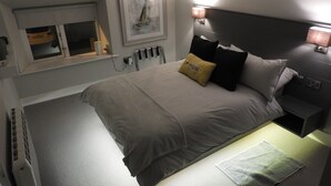 Un lit bien fait, avec une tête de lit, des lampes de chevet et une fenêtre donnant sur un beau paysage.
