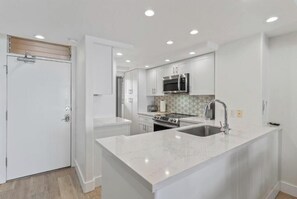A modern kitchen with white cabinetry, a central island with a sink, and built-in appliances.