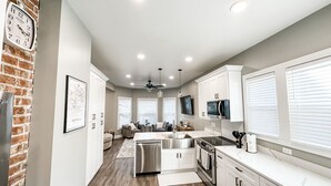 A modern kitchen with white cabinets, stainless steel appliances, and a brick accent wall.