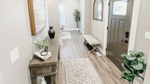 A hallway with a wooden bench, a rug, and a potted plant.