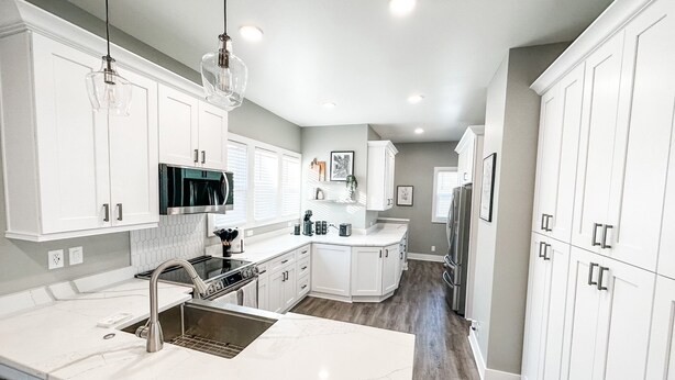 A modern kitchen with white cabinetry, a large island with a sink, and stainless steel appliances.