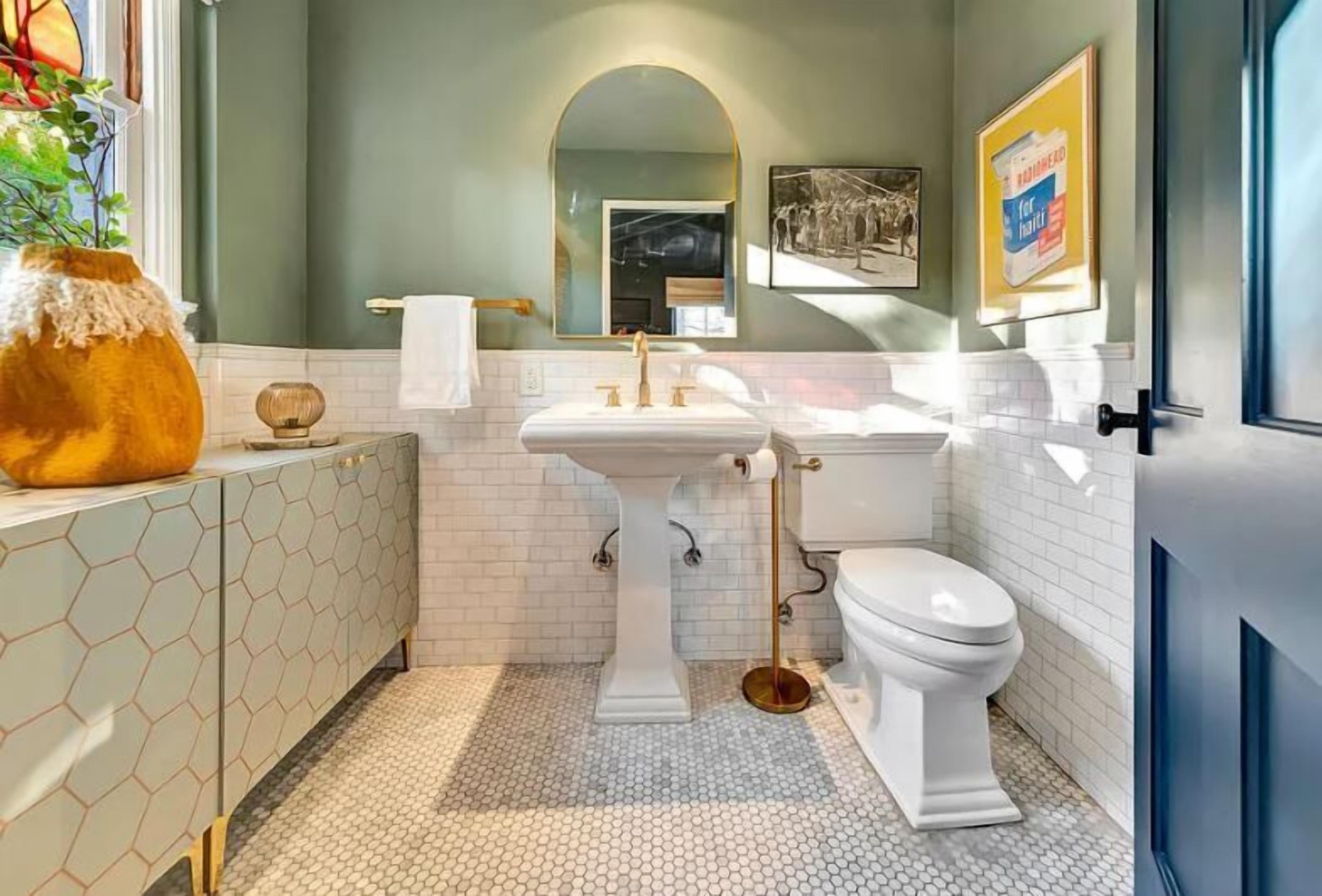 Un baño con lavamanos pedestal blanco, inodoro y tocador con patrón hexagonal.