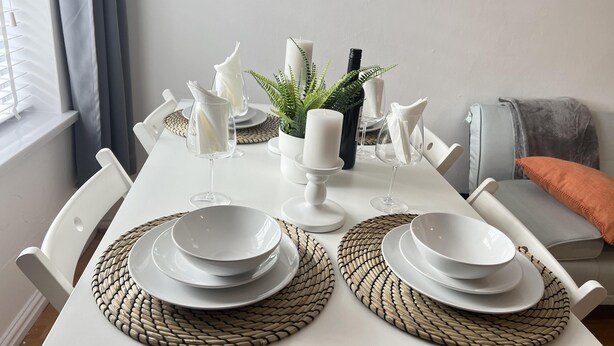 A dining table set with white plates, bowls, and glasses, accompanied by candles and a potted plant. - Cozy and Central City Apartment in Liverpool (Liverpool)