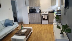 A compact living space with a kitchenette, a sofa, a coffee table, and potted plants. - Cozy and Central City Apartment in Liverpool (Liverpool)