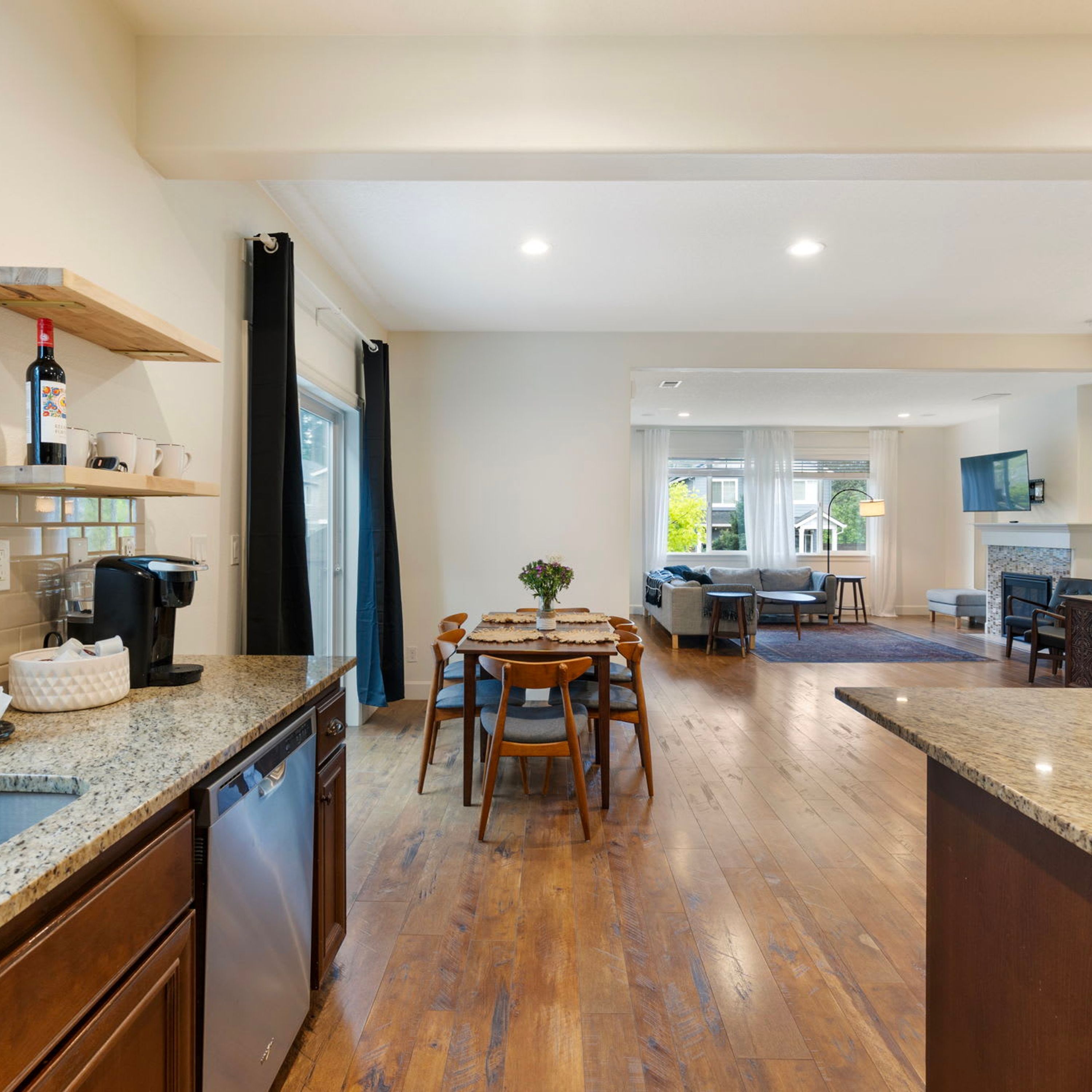 A modern kitchen with a dining area, wooden flooring, and a coffee station.