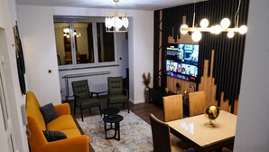A modern living room with a sofa, chairs, a dining table, and a TV mounted on the wall. - Urban Luxury Apartment Zagreb (Zagreb)