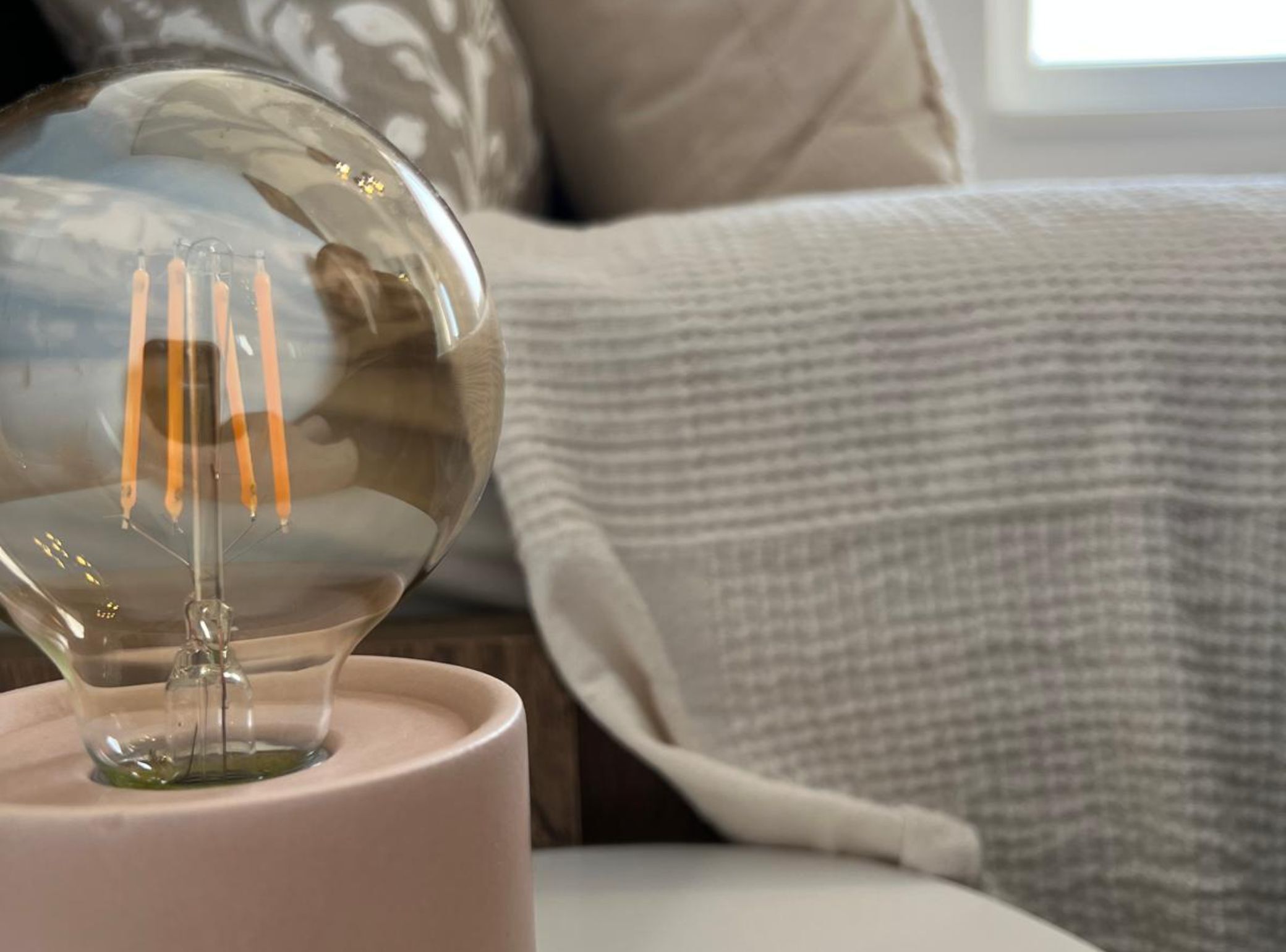 A clear glass object with a stem and three orange tubes, placed on a surface with a textured fabric in the background.