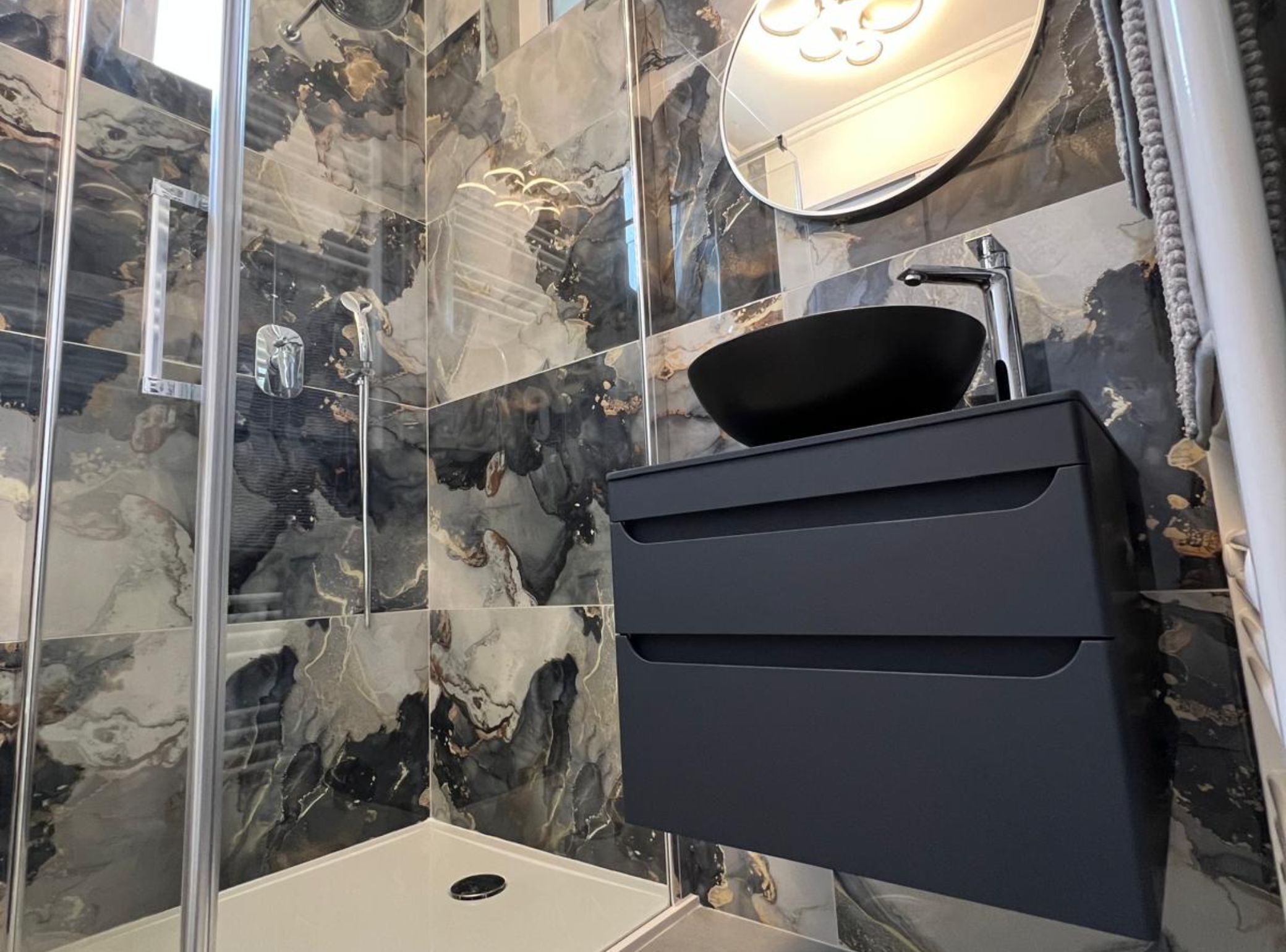 Une salle de bain avec un meuble-lavabo noir, un miroir et un lavabo.