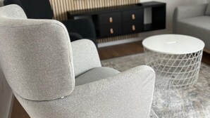 A modern living room with a grey sofa, a white round coffee table, and a TV mounted on a wooden panel wall. - Urban Luxury Apartment Zagreb (Zagreb)