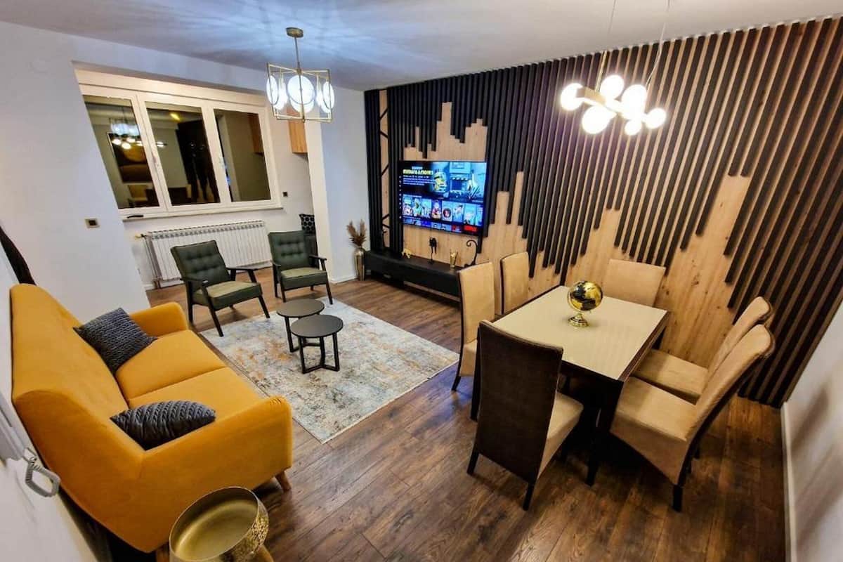 A modern living room with a sofa, chairs, a coffee table, and a TV.