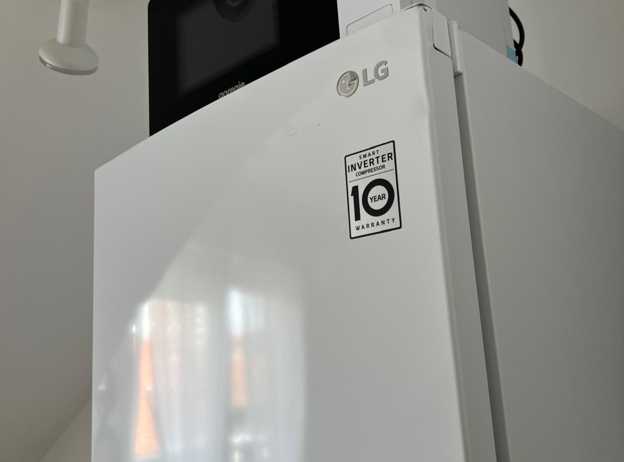 A white LG inverter compressor refrigerator with a 10-year warranty sticker.