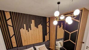 A modern bedroom with a bed, a mirror, and a unique geometric wall design. - Urban Luxury Apartment Zagreb (Zagreb)