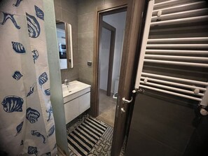 A bathroom with a sink, mirror, and towel rack.