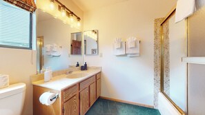 Une salle de bain équipée d’un lavabo, d’un miroir, d’un porte-serviettes et d’un espace douche.