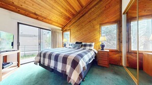 A wooden-paneled bedroom with a large bed, a desk, and a window with blinds. - Large Rustic Home. Private Washer/Dryer, Centrally Located. Pool On-site (Mammoth Lakes)