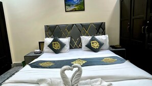 A hotel room with a bed, a nightstand, a wardrobe, and a ceiling with a decorative pattern. - Sapphire Inn (Islamabad)