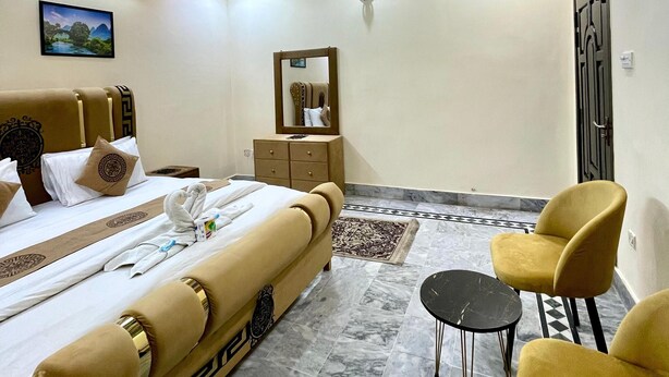 A hotel room with a bed, a desk, a chair, and a mirror. - Sapphire Inn (Islamabad)