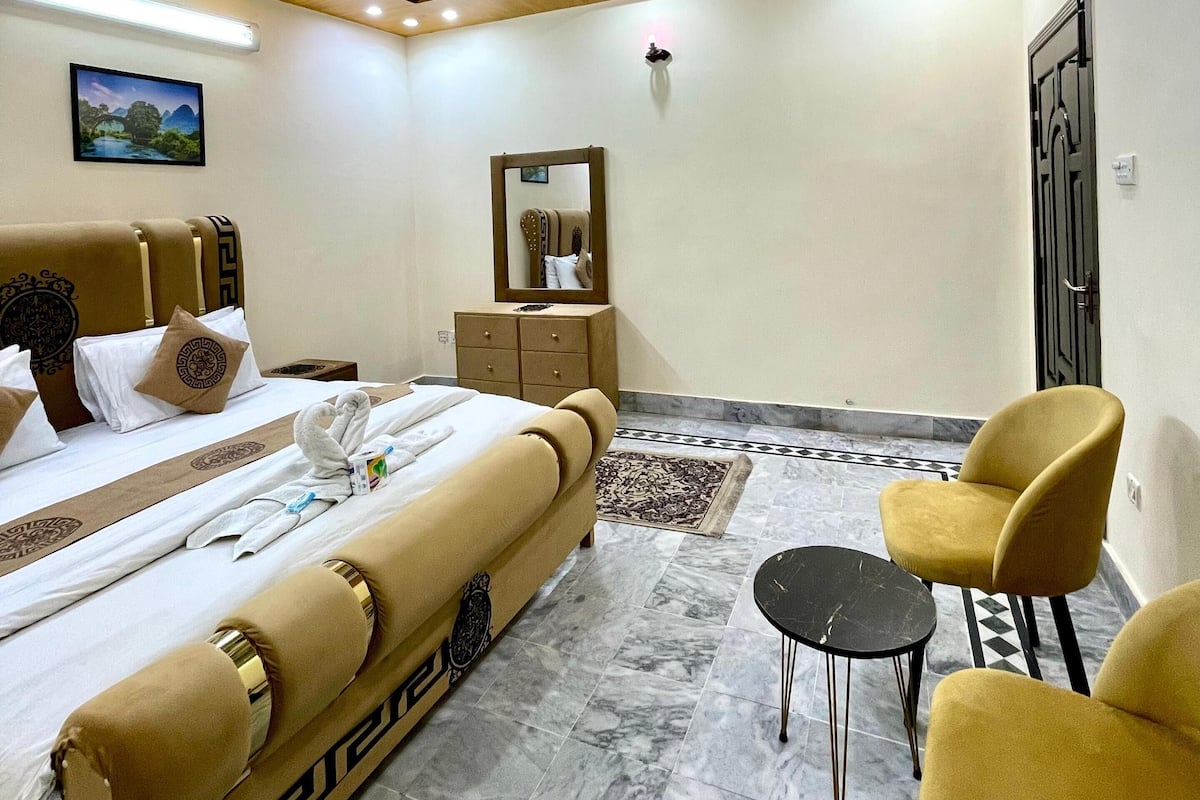 A hotel room with a bed, a desk, a chair, and a mirror.