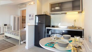Cocina compacta con refrigerador, mesa de comedor con platos y cubiertos, y un microondas sobre la estufa.