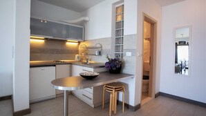 Una cocina moderna con una isla central, electrodomésticos de acero inoxidable y un taburete pequeño.