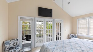 Ein Schlafzimmer mit einem Bett, einem Sessel, einem Schreibtisch und einem Fernseher an der Wand.