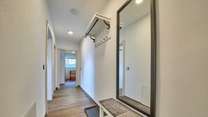 A narrow hallway with a bench, a large mirror, and a wall-mounted air conditioning unit. - Haus Joan - Apartments (Saalbach-Hinterglemm)