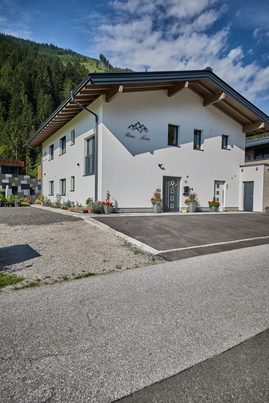 A modern building with a white facade, a mountain logo, and a parking area.