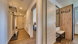 A modern hotel hallway with wooden flooring, a bench, and a mirror. - Haus Joan - Apartments (Saalbach-Hinterglemm)