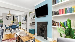 Ein modernes Wohnzimmer mit Kamin, Flachbildfernseher und einer Bücherwand voller Bücher.